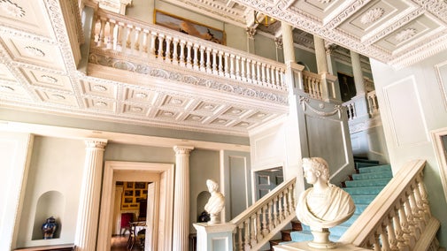 The staircase hall featuring delicate plasterwork and a balcony.